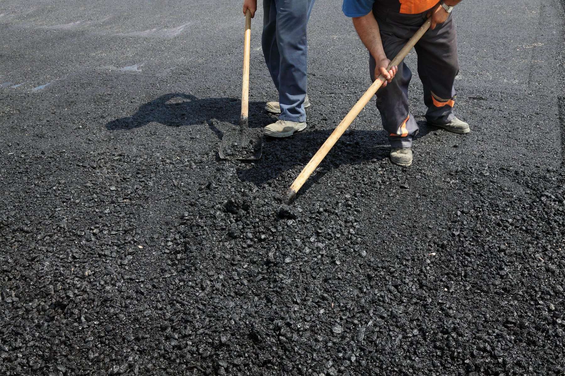 A hot asphalt mix is placed to repair the damaged parking lot.