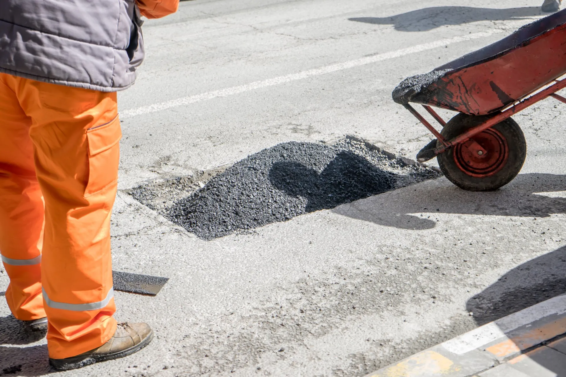To make the asphalt driveway safe again, contractors uses an asphalt mix to repair the potholes.